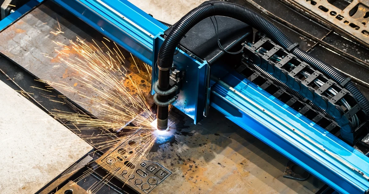 A CNC laser cutting machine slices through a metal sheet, generating bright sparks.